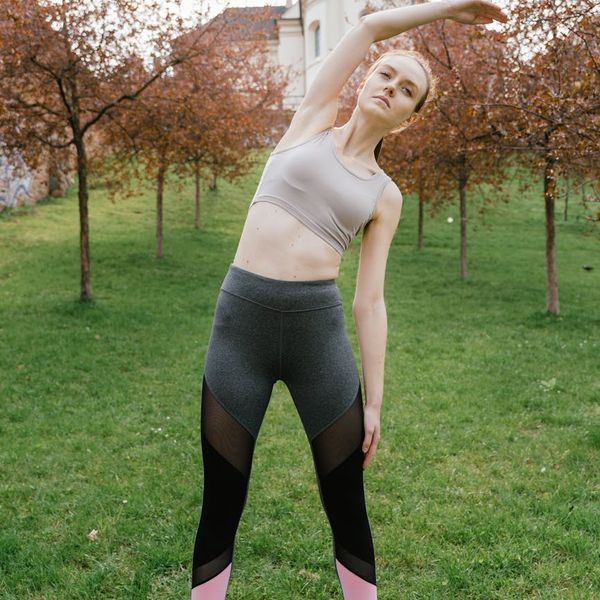 Woman performing an energetic yoga pose against a dark background.